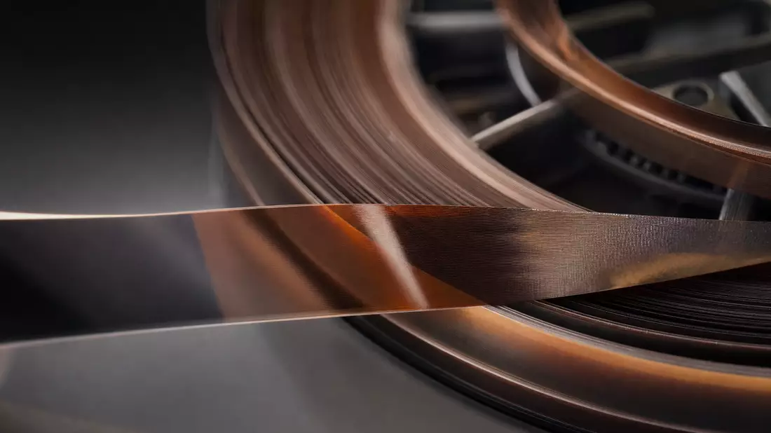 Extreme Makroaufnahme eines glänzenden Magnetbandes auf Spule in Amber und Dunkelgrau