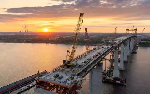 Jacobs Solutions Infrastrukturprojekt zeigt großen Brückenbau über einen Fluss bei Sonnenuntergang, ISIN US4698141098 - Foto: THN