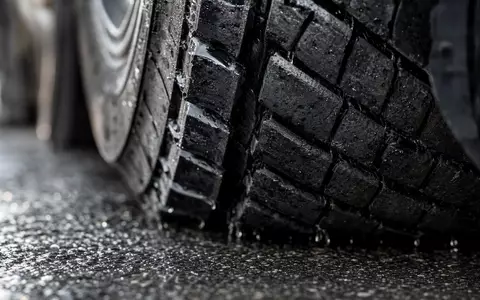 J.B. Hunt Transport US4655621062 – Makroaufnahme eines nassen LKW-Reifenprofils auf regennassem Asphalt mit Wassertropfen - Foto: THN