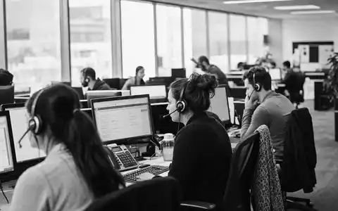 Dokumentarische Schwarzweiß-Aufnahme eines belebten Kundenservice-Büros veranschaulicht Teleperformance SE, ISIN FR0000051807, im weltweiten BPO-Geschäftsfeld - Foto: THN