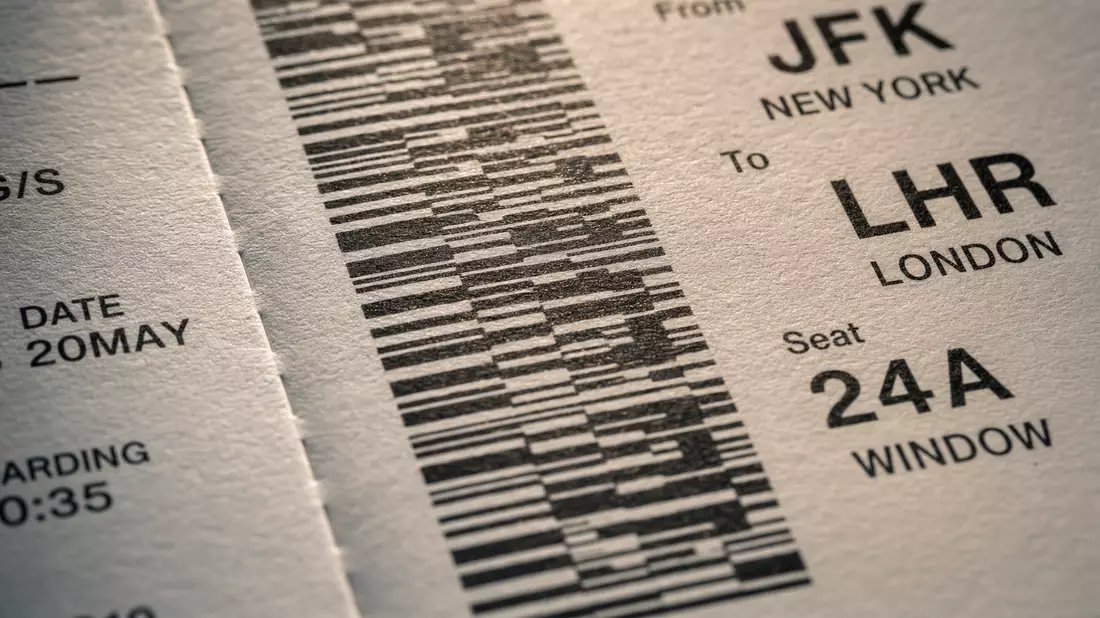 Extreme macro close-up of boarding pass barcode strips on textured paper, sharp black bars with flight route codes, shallow depth of field, warm side-lighting