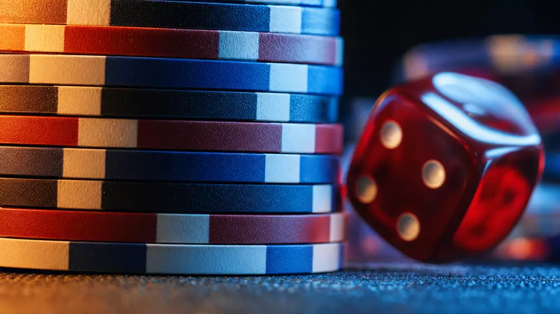 Extreme Nahaufnahme gestapelter Pokerchips und eines roten Würfels mit dramatischem Licht