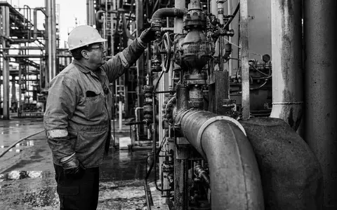 Lanxess AG (DE0005470405) zeigt einen Anlagentechniker bei der Wartung von Rohrleitungen in Schwarzweiß - Foto: THN