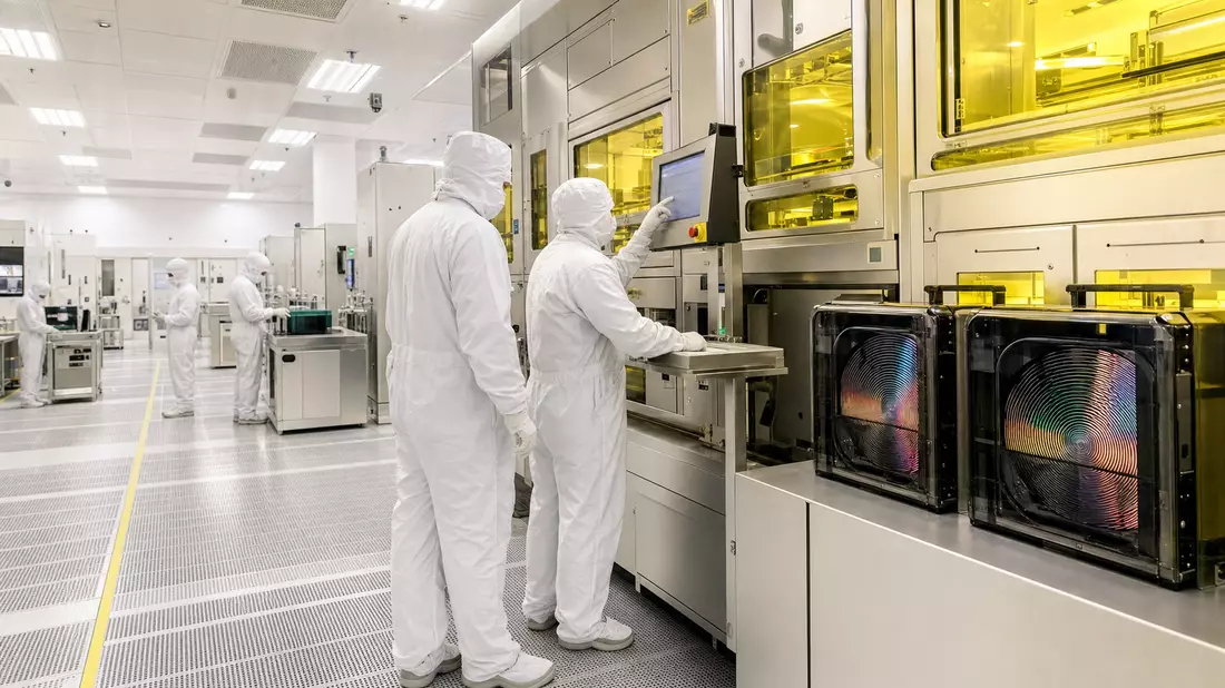 Techniker im Reinraum an Halbleiter-Fertigungsanlage mit gelber Sicherheitsbeleuchtung
