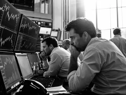 IG Group Holdings plc, ISIN GB0004726096, dokumentarisches Schwarzweißfoto zeigt Händler konzentriert vor Bildschirmen im Büro - Foto: THN