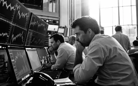 IG Group Holdings plc, ISIN GB0004726096, dokumentarisches SchwarzweiĂfoto zeigt HĂ€ndler konzentriert vor Bildschirmen im BĂŒro - Foto: THN