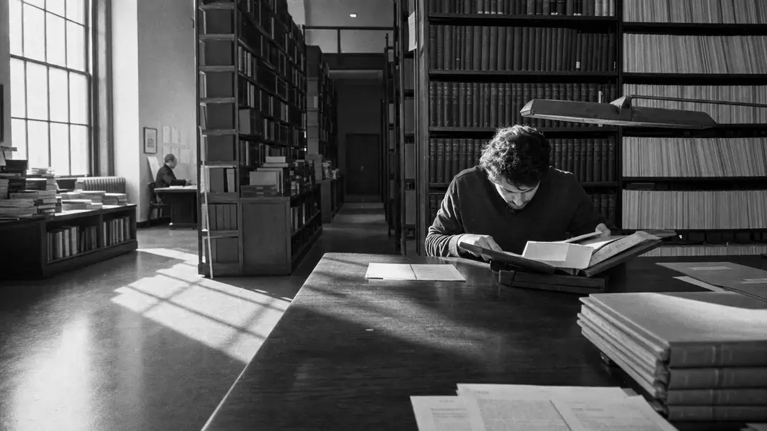 Schwarzweiß-Reportagefoto eines Bibliotheksarchivs mit Forscher, Sinnbild für RELX plc