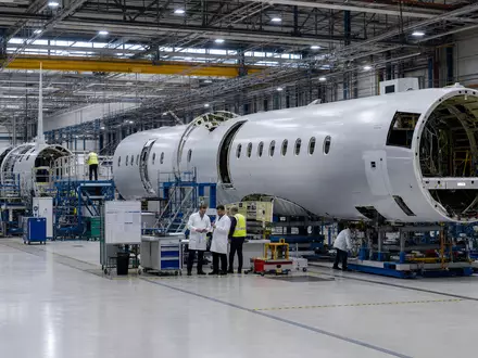 Dassault Aviation SA (FR0000121725): Industrielle Montagehalle zeigt Flugzeugrumpf-Sektionen, während Techniker sorgfältig die Bauteile prüfen - Foto: THN