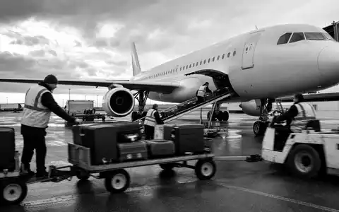 Dokumentarische Schwarzweiß-Aufnahme von Flughafenpersonal beim Beladen eines Flugzeugs zeigt Air France-KLM SA FR0000031122 - Foto: THN