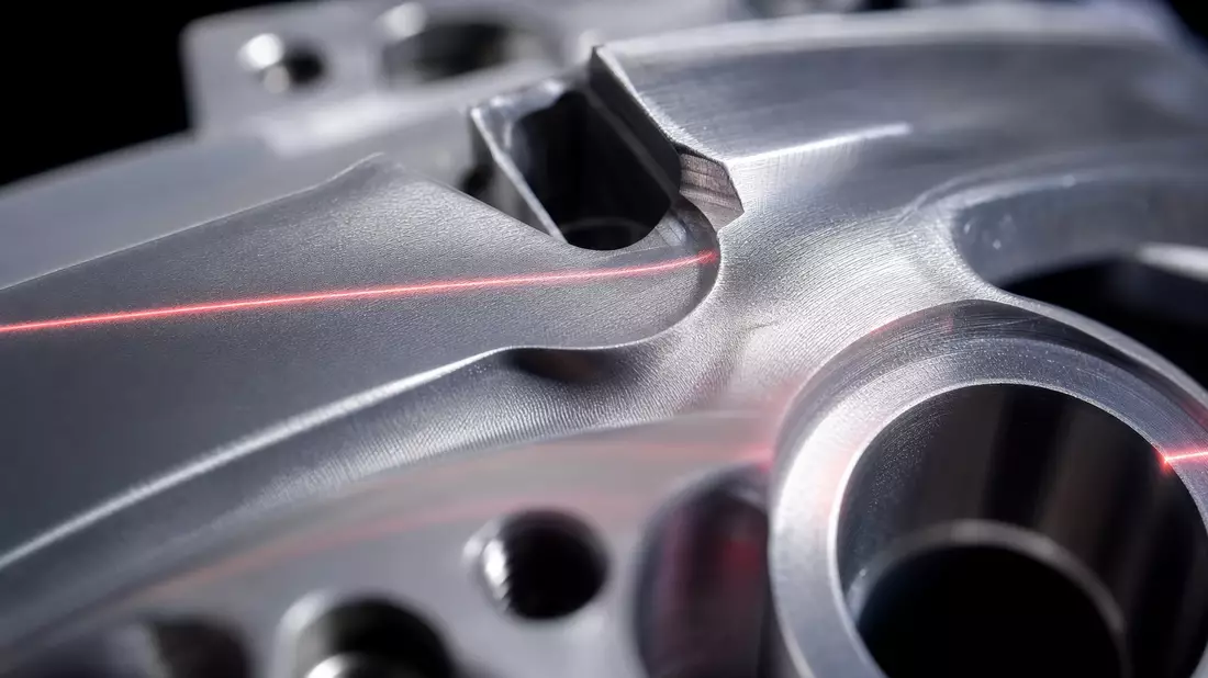Makroaufnahme einer Metalloberfläche mit rotem Laserstrahl und Bearbeitungsspuren