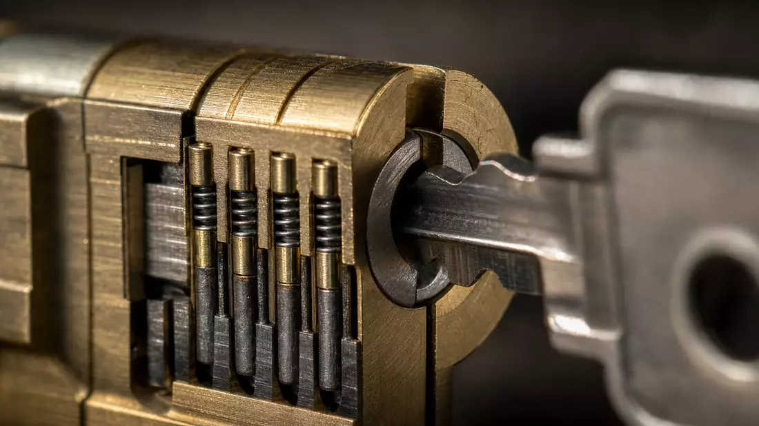 Makroaufnahme eines Messing-Türzylinders mit Metallschlüssel und Stiften