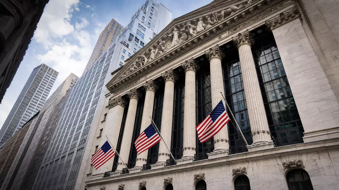 Editorialfoto der NYSE-Fassade mit Säulen und amerikanischen Flaggen im Wind
