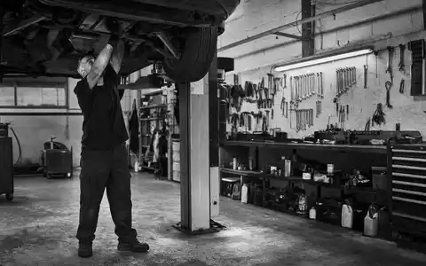 O'Reilly Automotive (US67103H1077) Aktienbild: Schwarzweiß-Reportagefoto eines Mechanikers in einer Kfz-Werkstatt bei der Arbeit - Foto: THN