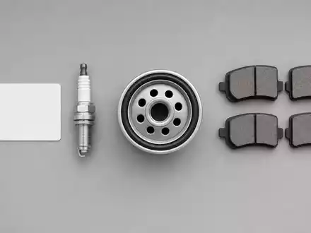 O'Reilly Automotive (US67103H1077) Aktienbild: Flatlay-Fotografie mit ISIN-Karte, Zündkerze, Ölfilter und Bremsklötzen auf grauem Hintergrund - Foto: THN