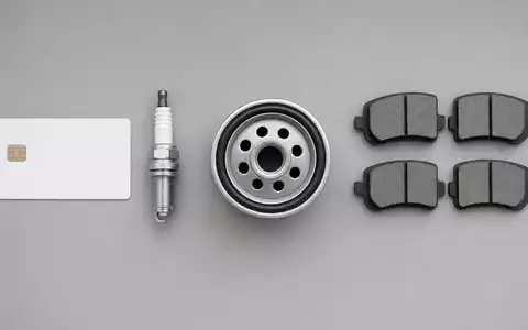 O'Reilly Automotive (US67103H1077) Aktienbild: Flatlay-Fotografie mit ISIN-Karte, Zündkerze, Ölfilter und Bremsklötzen auf grauem Hintergrund - Foto: THN