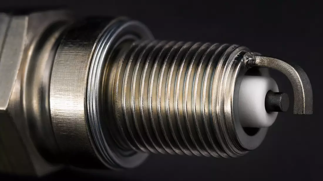 Extreme Nahaufnahme des Metallgewindes und der Keramikspitze einer Zündkerze