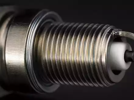 O'Reilly Automotive (US67103H1077) Aktienbild: Makrofotografie einer Zündkerze mit sichtbarem Metallgewinde und Keramikisolator - Foto: THN