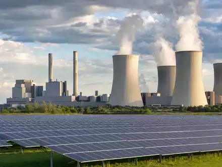 NRG Energy Inc. US6293775085 zeigt generisches Kraftwerk mit Kühltürmen und vorgelagerter Solar-Farm bei Tageslicht - Foto: THN