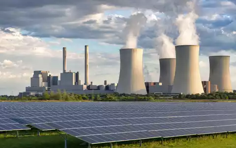 NRG Energy Inc. US6293775085 zeigt generisches Kraftwerk mit Kühltürmen und vorgelagerter Solar-Farm bei Tageslicht - Foto: THN