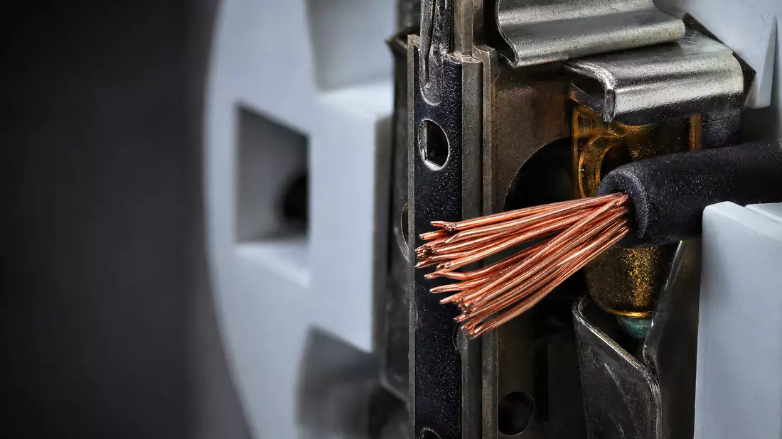 Extreme Makroaufnahme einer Steckdose mit freiliegenden glänzenden Kupferdrähten