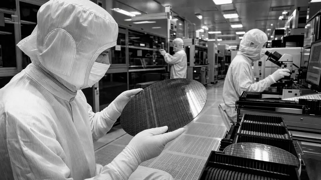 Schwarzweißfoto von Ingenieuren im Reinraumanzug mit Silizium-Wafer