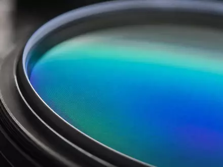 EssilorLuxottica FR0000121667 zeigt Makroaufnahme einer Brillenlinse mit schillernder Antireflexbeschichtung in detailreicher blaugrüner Nahaufnahme - Foto: THN