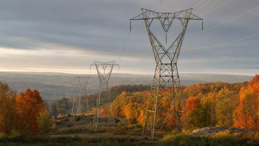 Hochspannungsmasten in New-England-Herbstlandschaft mit Stromleitungen im goldenen Abendlicht