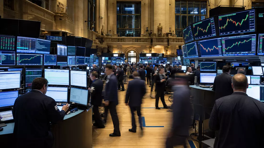 NYSE-Handelssaal mit Händlern, Großbildschirmen und grün-roten Kursverläufen der Versorger