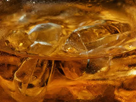 Diageo plc GB0002374006 zeigt eine Makroaufnahme bernsteinfarbener Spirituose mit Eiswürfeln und feinen Kondenswassertropfen im Glas - Foto: THN