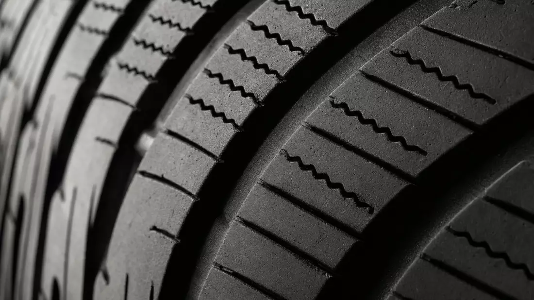 Extreme Makroaufnahme eines schwarzen Reifenprofils mit feinen Rillen und Texturen
