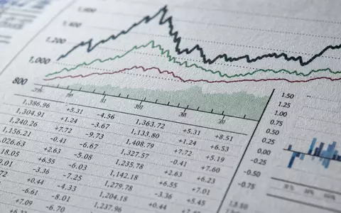 Man Group plc JE00BJ1DLW90 zeigt Makroaufnahme von Finanzdaten, Diagrammlinien und Zahlenreihen auf gedrucktem Papier - Foto: THN