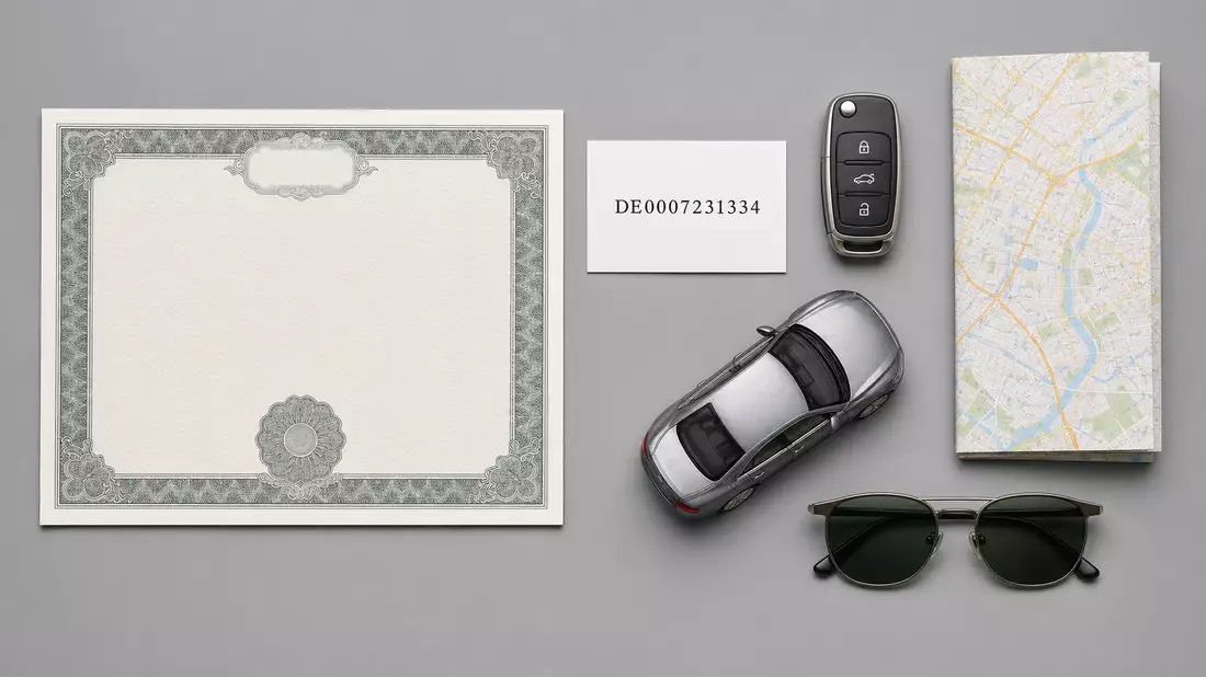 Flatlay mit Zertifikat, ISIN-Karte, Autoschlüssel, Modellauto und Sonnenbrille