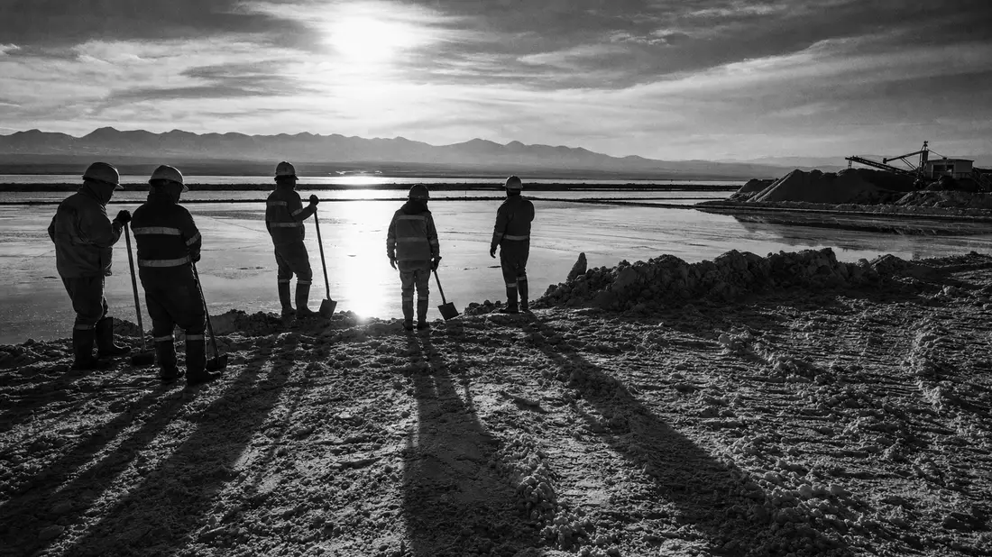 Schwarz-Weiß-Reportagefoto von Bergarbeitern am Lithium-Salzsee im Gegenlicht