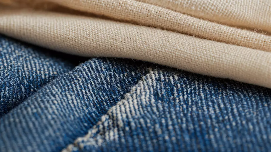 Extreme Nahaufnahme von gefalteter Baumwoll- und Jeansstoff-Textur in Blau und Beige