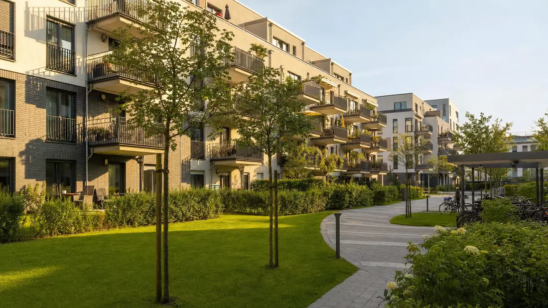 Moderne Wohnanlage mit Balkonen und Grünflächen im Sonnenlicht