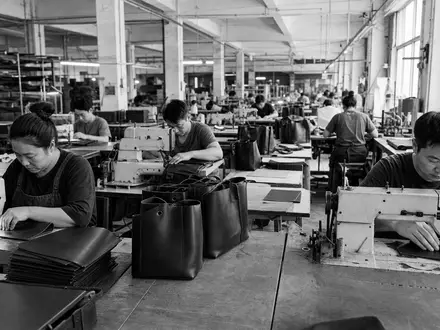Schwarzweiße Reportagefotografie dokumentiert Fabrikarbeiter beim Nähen von Ledertaschen für Tapestry Inc. US8760301072 Investment - Foto: THN