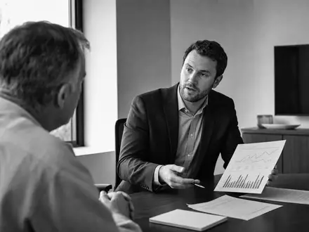 Raymond James Financial US7547301090 dokumentiert eine SchwarzweiĂź-Beraterberatung mit Portfolio-Unterlagen in einem modernen Besprechungsraum - Foto: THN