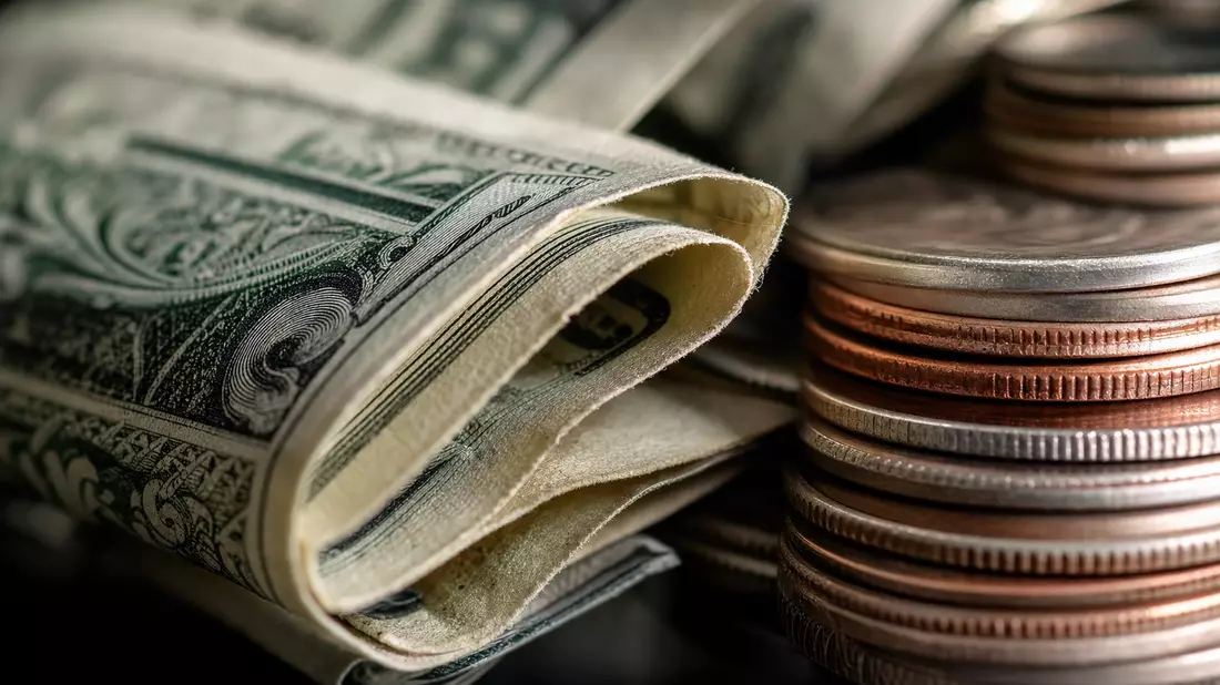Extreme Nahaufnahme von gefalteten Dollarnoten und gestapelten Münzen