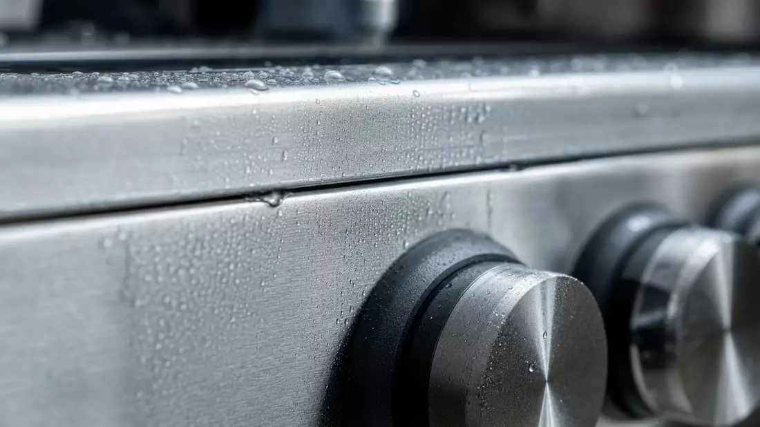 Makroaufnahme einer gebürsteten Edelstahloberfläche mit Wassertropfen