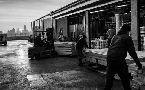 Kingfisher plc GB0033195214 dargestellt als dokumentarische Schwarzweiß-Reportage an einer Warenlogistik-Laderampe bei Sonnenaufgang - Foto: THN