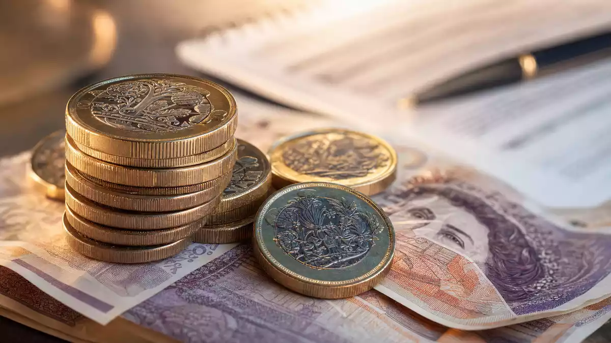Makroaufnahme von britischen Pfund-Münzen und Geldscheinen mit unscharfem Dokument