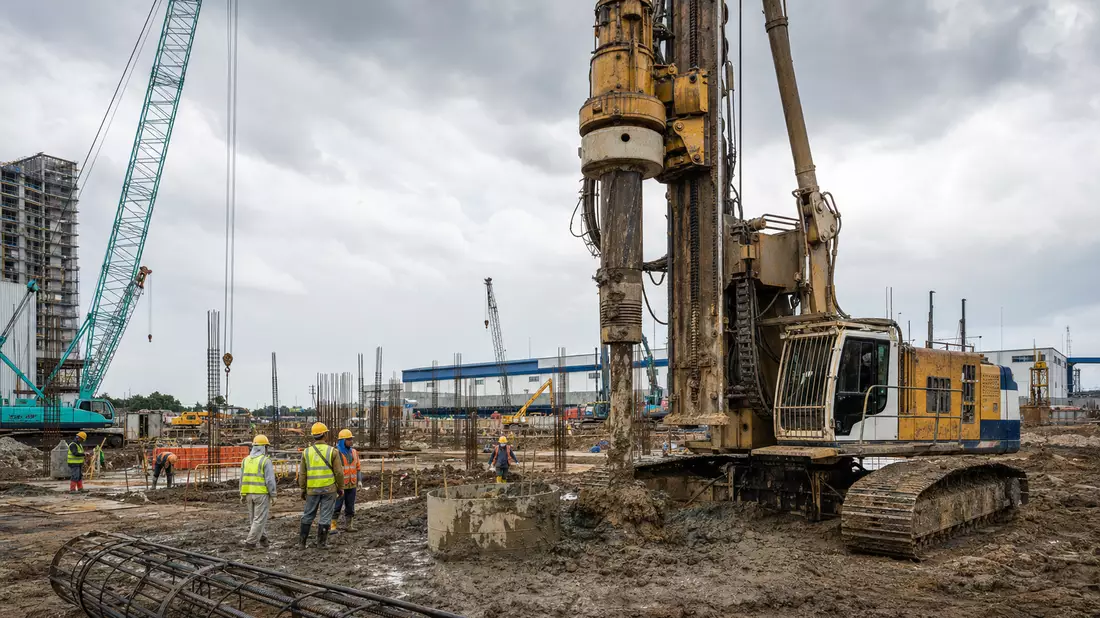 Fotorealistische Baustelle mit Bohrgerät für Spezialtiefbau und Baukran im Hintergrund