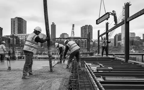Schwarzweiß-Reportage dokumentiert Bauarbeiter, passend zu Morgan Sindall Group plc, ISIN GB0006005892, im Baugewerbe tätig - Foto: THN