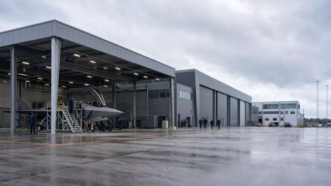 Fotorealistischer Flugzeughangar mit Technikern an Rüstungsstandort in Skandinavien