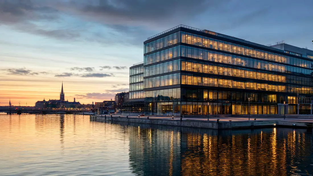 Modernes Glasgebäude am Stockholmer Hafen bei Dämmerung, Symbolbild für Kinnevik AB