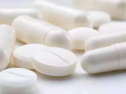 GSK plc (ISIN GB0009252882) zeigt in der Makroaufnahme weiße Tabletten und Kapseln in extremer Nahaufnahme - Foto: THN