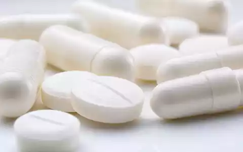 GSK plc (ISIN GB0009252882) zeigt in der Makroaufnahme weiße Tabletten und Kapseln in extremer Nahaufnahme - Foto: THN