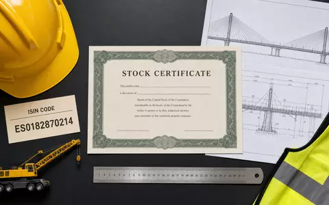 Flatlay mit Aktienzertifikat und ISIN-Karte ES0182870214 repräsentiert Anlagethema Sacyr S.A. für Investoren anschaulich - Foto: THN