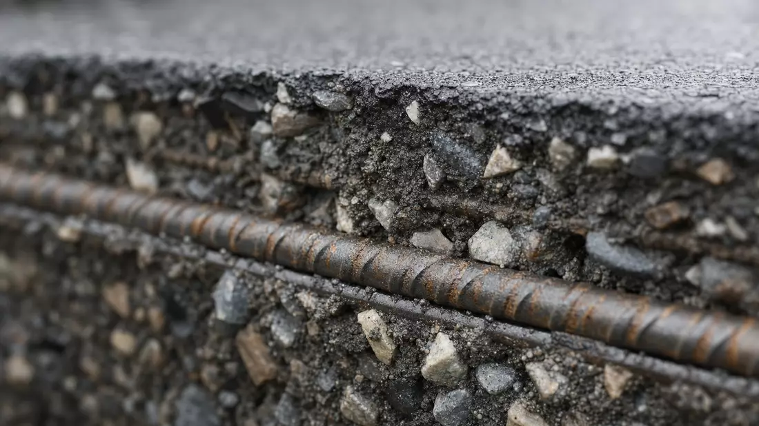 Makroaufnahme von Asphalt mit Stahlbewehrung und Betonzuschlagstoffen im Detail