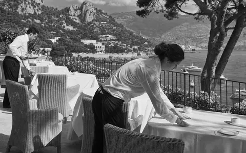 Meliá Hotels International S.A. dokumentarisch in Schwarzweiß: Hotelpersonal deckt Frühstückstisch auf Terrasse, ISIN ES0176252718 - Foto: THN